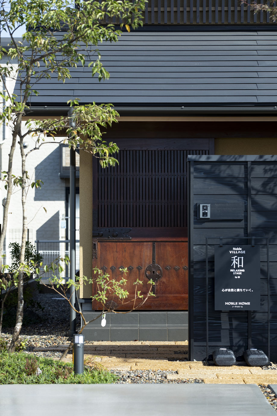 黒い縦格子の建具に木製の門扉を組み合わせた門まわり
